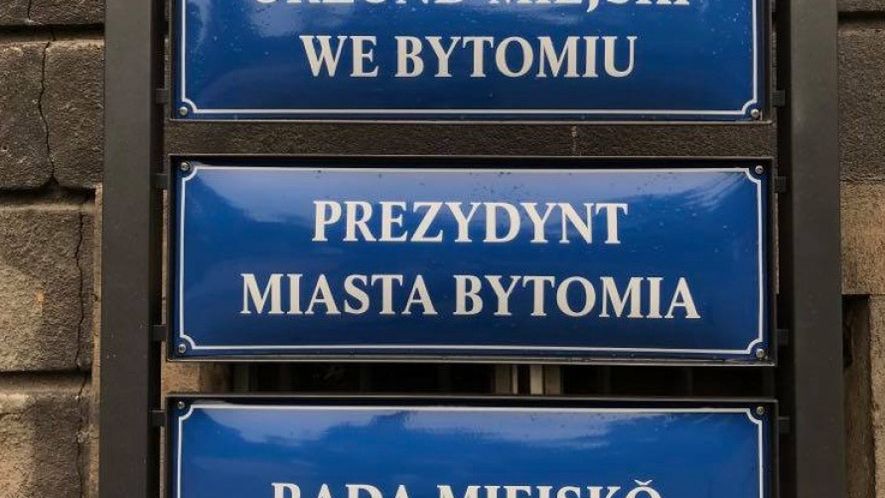 Śląskie. Na budynku Urzędu Miejskiego w Bytomiu zawisły flagi województwa śląskiego, a przed wejściem do budynku tabliczki urzędowe po śląsku.