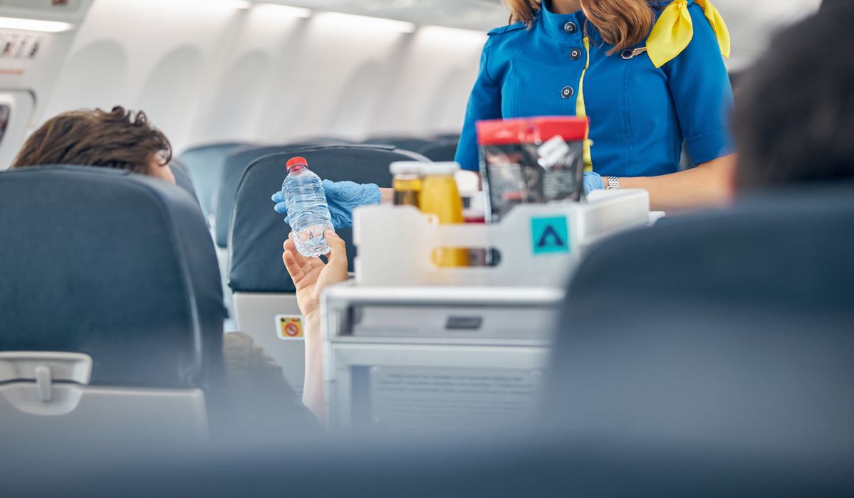 Stewardessa o jedzeniu w samolocie i turystach, fot. Adobe Stock