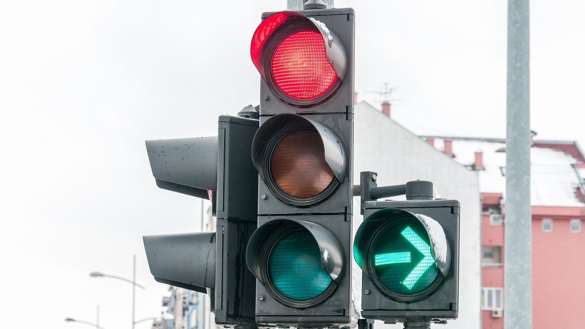 Na zdjęciu sygnalizator świetlny świecący się na czerwono wraz z zieloną strzałką