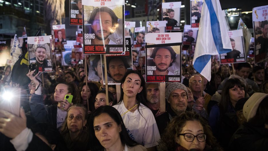 TEL AVIV, ISRAEL - JANUARY 13:  People hold photos of hostages  during a rally to mark 100 days of captivity for hostages by Hamas in Gaza on January 13, 2024 in Tel Aviv, Israel. The protest featured a 30-meter-long tunnel meant to simulate the conditions in which Israeli hostages are allegedly held in Gaza. More than 100 Israeli hostages captured on Oct. 7 remain held in Gaza by Hamas and other militant groups, according to Israeli authorities.  (Photo by Amir Levy/Getty Images)