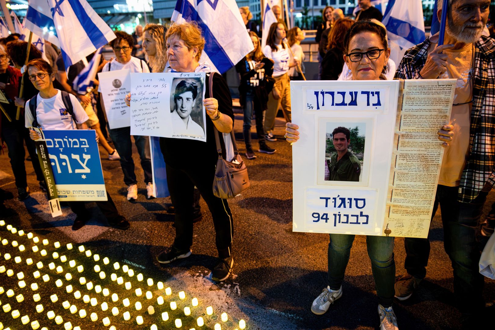 TEL AVIV, ISRAEL - 2023/04/22: Bereaved family members hold placards with photos of their loved ones, next to thousands of "Yom HaZikaron" candles for the Memorial Day of the fallen Israeli soldiers and terror attacks victims during an anti-judicial overhaul demonstration in Tel Aviv. (Photo by Matan Golan/SOPA Images/LightRocket via Getty Images)