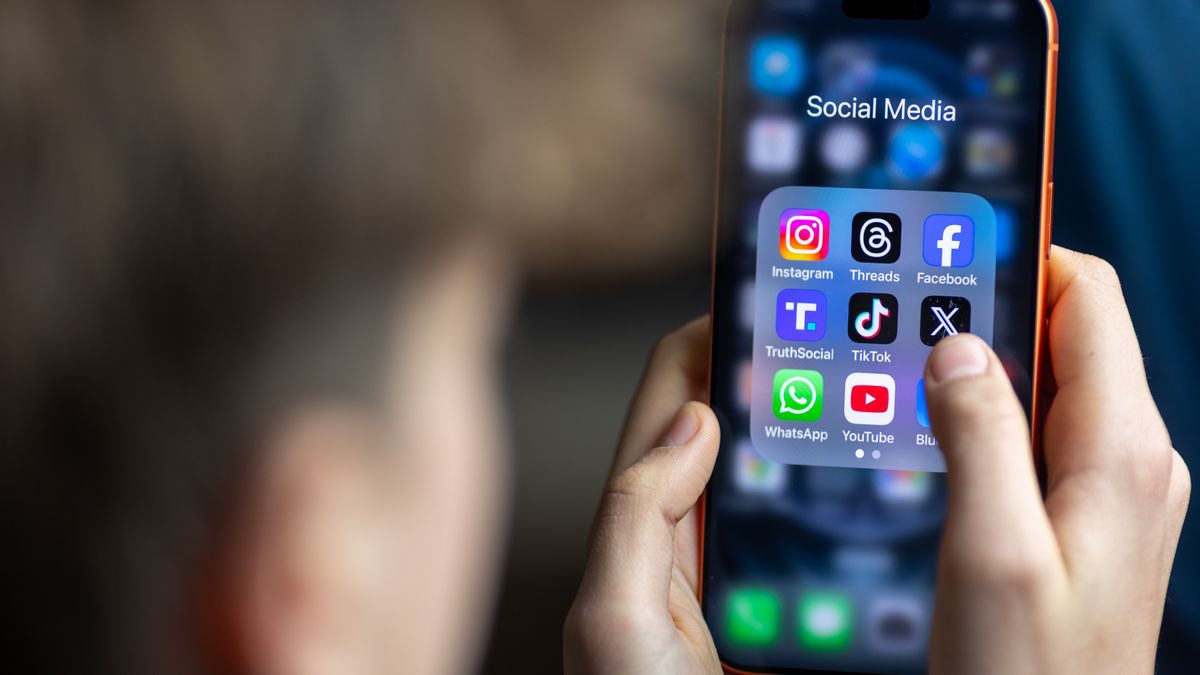 BATH, UNITED KINGDOM - MARCH 29: In this photo illustration a 14-year-old boy holds an iPhone screen displaying various social media and messaging apps on March 29, 2026 in Bath, England. On top row left to right, the logo of social media platform Instagram is seen beside that of Meta’s Threads and Facebook. On the middle row from left is the logo of Donald Trump's Truth Social app, next to the logo of social media app TikTok and the logo of Elon Musk’s US online social media and social networking site 'X' (formerly known as Twitter). Along the bottom row, left to right is the messaging service WhatsApp, the logo for online video sharing and social media platform YouTube and the logo for the Bluesky app. In the UK, a ban on social media for under-16s has been backed by the House of Lords following the Australian law which aims to stop children under 16 from having social media accounts and social media platforms, including TikTok, Facebook, Snapchat, Reddit, X, formerly Twitter, and Instagram potentially being be fined for preventing children younger than 16 from having social media accounts. (Photo by Anna Barclay/Getty Images)