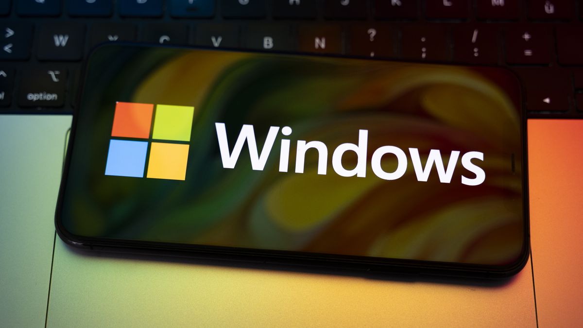 The Windows logo appears on the screen of a smartphone placed on a computer keyboard illuminated by orange and green light. Microsoft releases a major update to Windows 11 (25H2), and Windows 10 support ends permanently on October 14. In Creteil, France, on October 9, 2025. (Photo by Samuel Boivin/NurPhoto via Getty Images)