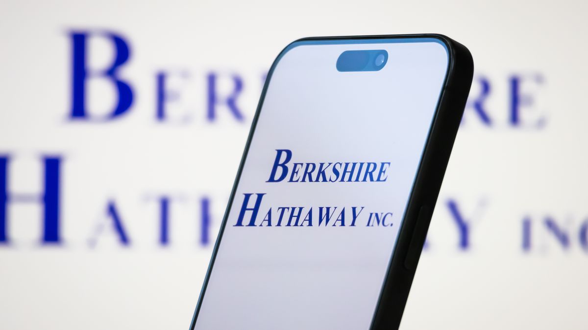 CHONGQING, CHINA - MAY 11: In this photo illustration, the logo of Berkshire Hathaway Inc. is displayed on a smartphone screen, with the company's blue branding visible in the background, on May 11, 2025, in Chongqing, China. Berkshire Hathaway is a renowned American multinational conglomerate holding company led by Warren Buffett, with subsidiaries spanning insurance, railroads, utilities, manufacturing, retail, and financial services. (Photo illustration by Cheng Xin/Getty Images)