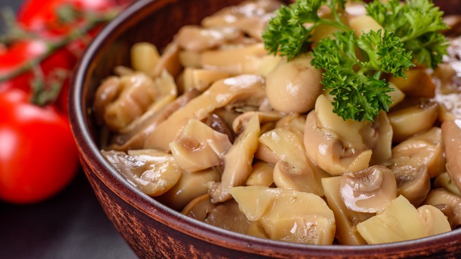 Fresh delicious spicy canned mushrooms with spices and herbs in ceramic dishes