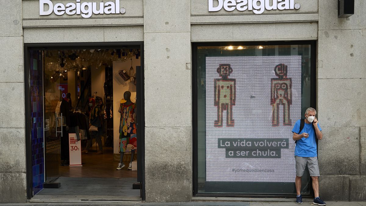 MADRID, SPAIN - JUNE 01: A man speaks on the phone at the door of the Desigual store next to a sign with the words ''Life will be cool again'' during phase one of the national plan to reopen the country, on June 01, 2020 in Madrid, Spain. Spain has largely ended the lockdown it imposed to curb the spread of Covid-19, which caused the death of more than 27,000 people across the country. (Photo by Carlos Alvarez/Getty Images)
