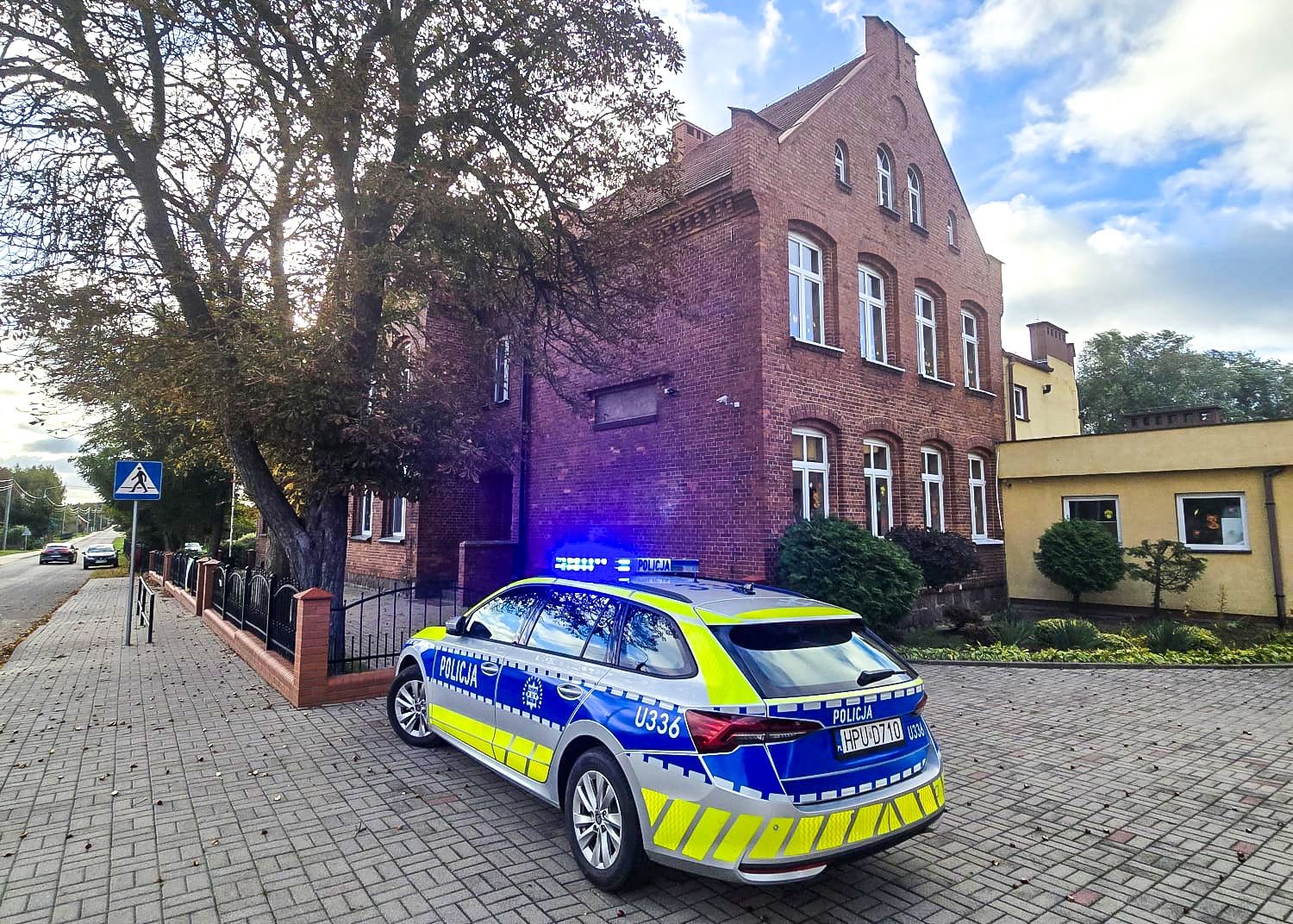 Radiowóz policji przed budynkiem szkoły w powiecie chodzieskim
