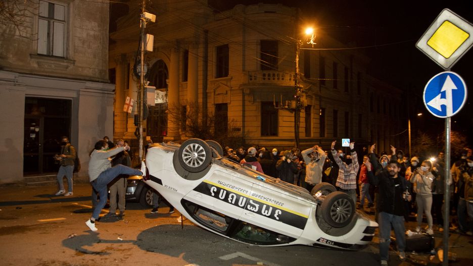 TBILISI, GEORGIA - MARCH 08: Protestors damage the police car as they clash with Police that are using water cannons, pepper spray and tear gas against protesters on March 8, 2023 in Tbilisi, Georgia. Thousands of protestors with EU and national flags gathered outside the Georgian parliament over night after the first reading of a controversial draft law that would require some organisations receiving foreign funding to register as "foreign agents" was accepted. Human Rights groups decry a breach of basic human rights. (Photo by Daro Sulakauri/Getty Images)