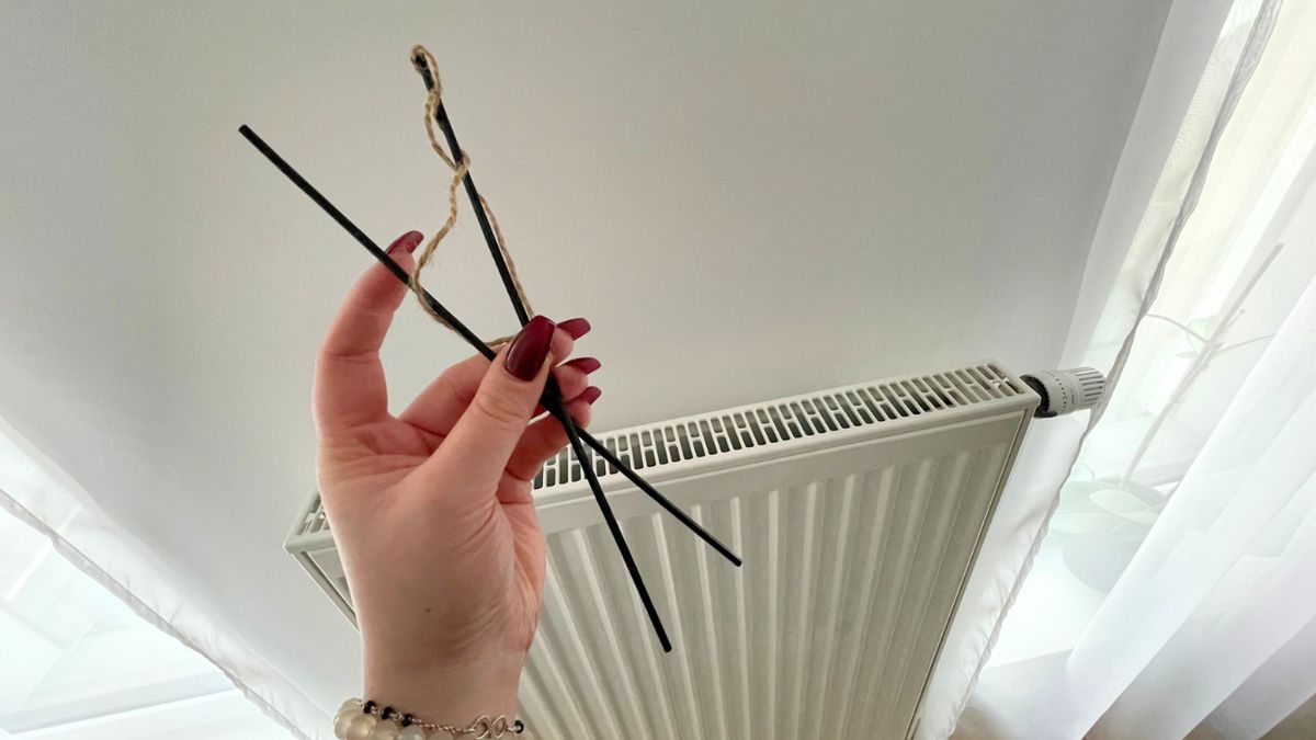 Ręka trzyma sznurek i dwa patyczki przy grzejniku