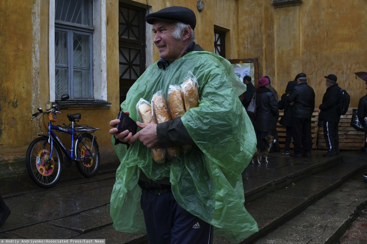 Mężczyzna dzierży paszport ukraiński i chleb, jaki dostał