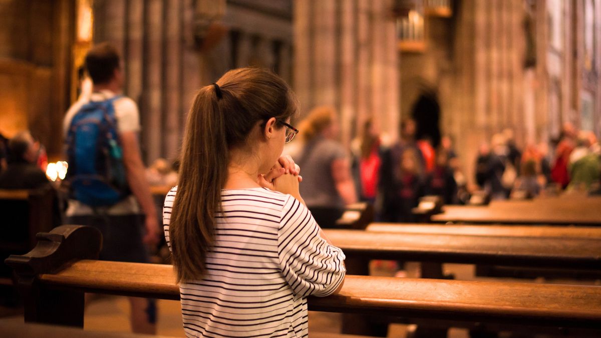 Dziewczynka klęczy i modli się w kościelnej ławce