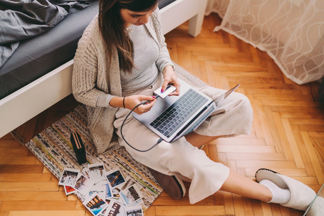 Woman at home unlocking external hard disk drive to print photos from laptop by using small portable printer