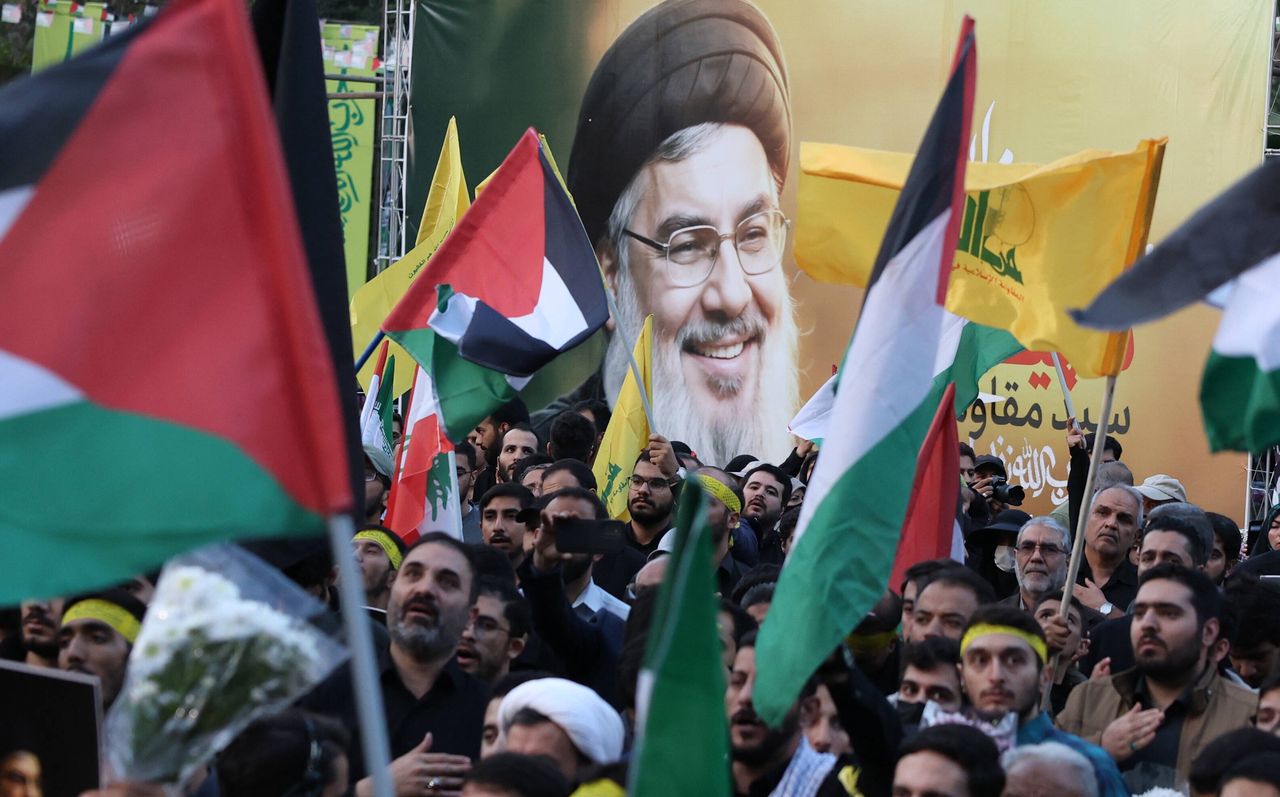 Iranians during a protest next to a photo of Hassan Nasrallah