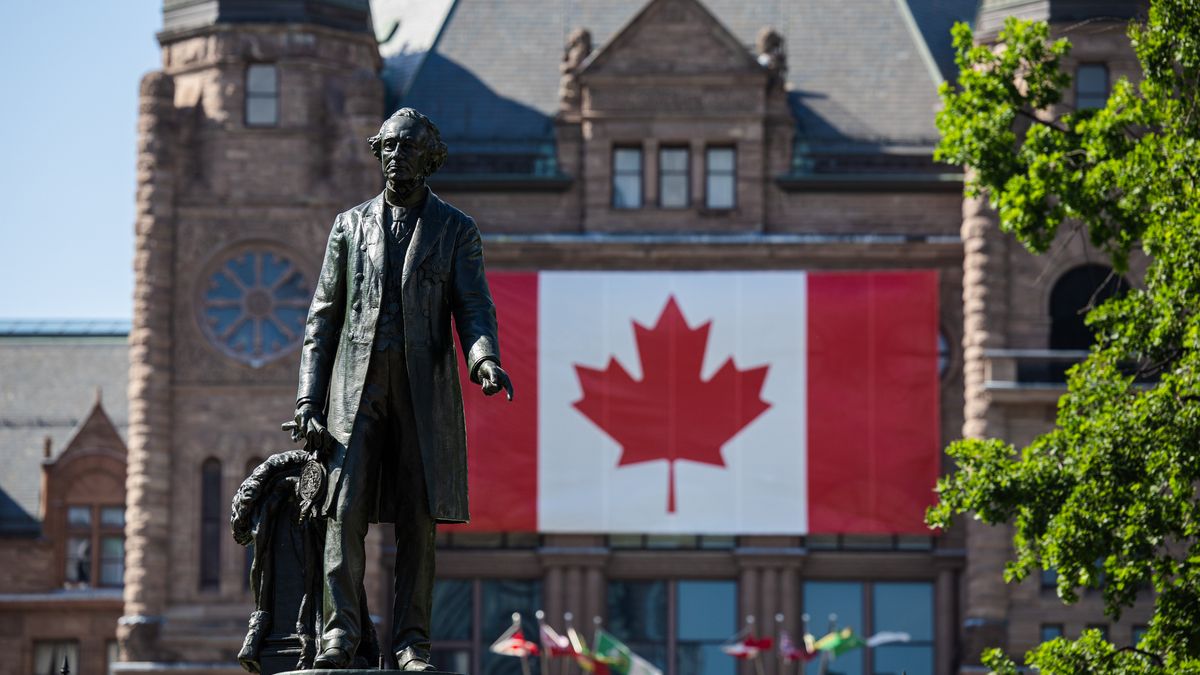 Toronto, ON - July 1: A large Canadian flag is seen on queens park behind the recently uncovered statue of John A Macdonald as a Canada Day celebration happens on the grounds of Queens Park. PD Nick Lachance/Toronto Star Nick Lachance/Toronto Star        (Nick Lachance/Toronto Star via Getty Images)