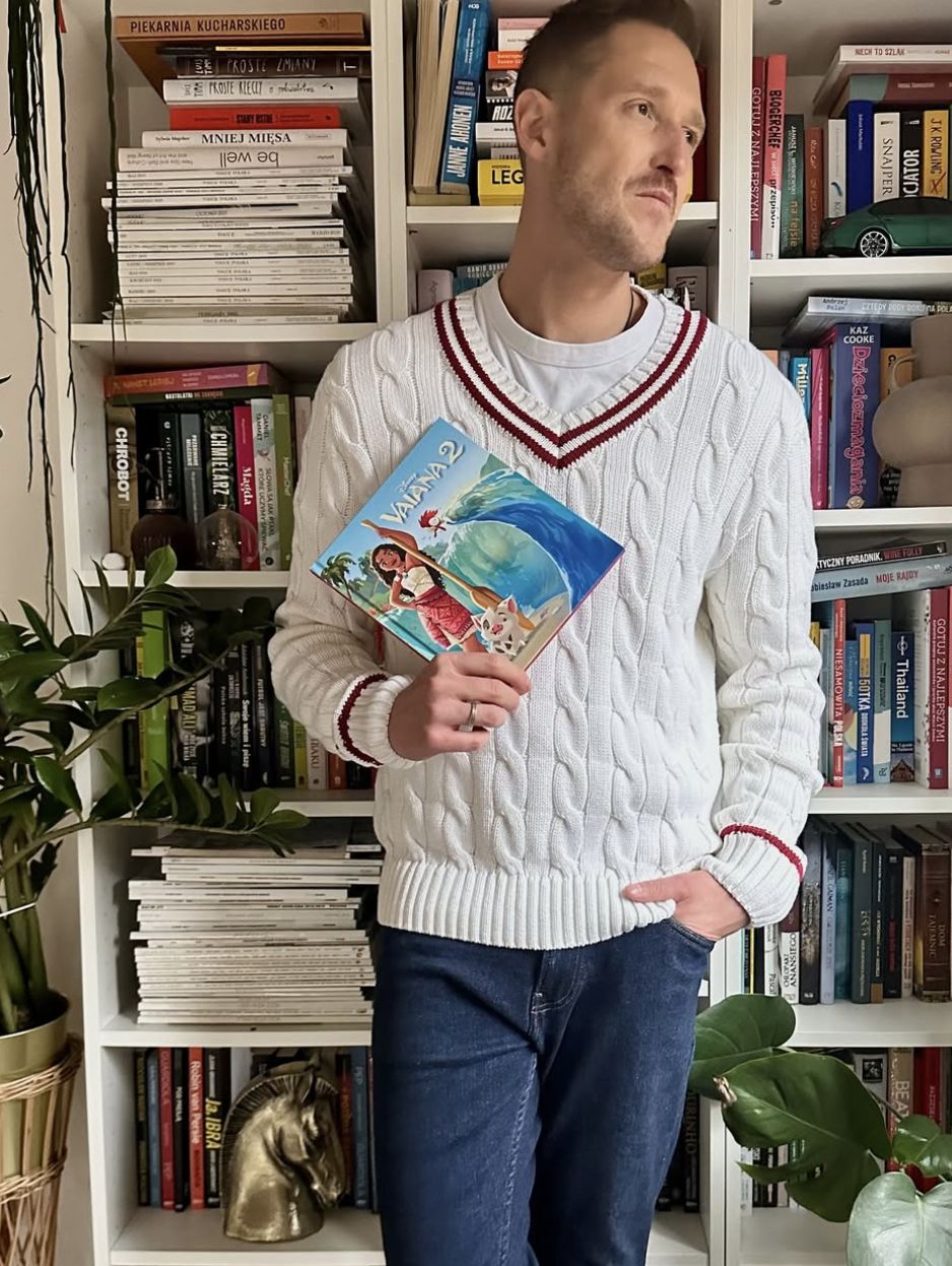 Damian Michałowski przy regale z książkami