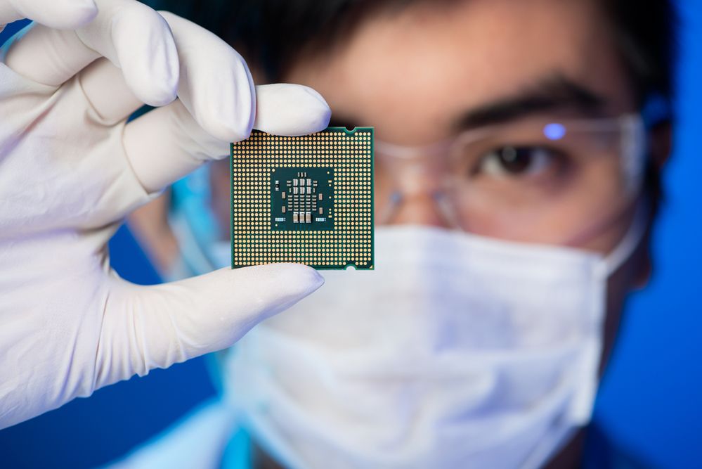 Zdjęcie Cropped image of an engineer showing a computer microchip on the foreground pochodzi z serwisu Shutterstock
