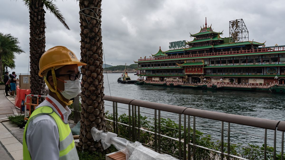 HONG KONG, CHINA - JUNE 14:  A worker looks out from the promenade as tugboats tow the Chinese imperial-style Jumbo Floating Restaurant out of a typhoon shelter in Aberdeen on June 14, 2022 in Hong Kong, China. The iconic Jumbo Floating Restaurant in Hong Kong is set to depart the city, amid a lack of funds to maintain the restaurant following months of COVID-19 restrictions. (Photo by Anthony Kwan/Getty Images)
