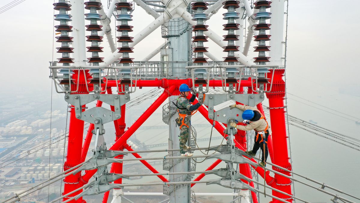 NANJING, CHINA - FEBRUARY 20, 2023 - Construction workers inspect the construction site of the world's 385-meter high power transmission tower, a 500-kv transmission line from Fengcheng to Meili in Nanjing, Jiangsu Province, China, Feb. 20, 2023. It is understood that when the project is completed and put into operation, new energy from the north bank of the Yangtze River will be continuously sent to the South of the Yangtze River, which will comprehensively improve the green and sustainable development capacity of the Yangtze River Delta and meet the daily demand of about 8 million households. (Photo credit should read CFOTO/Future Publishing via Getty Images)