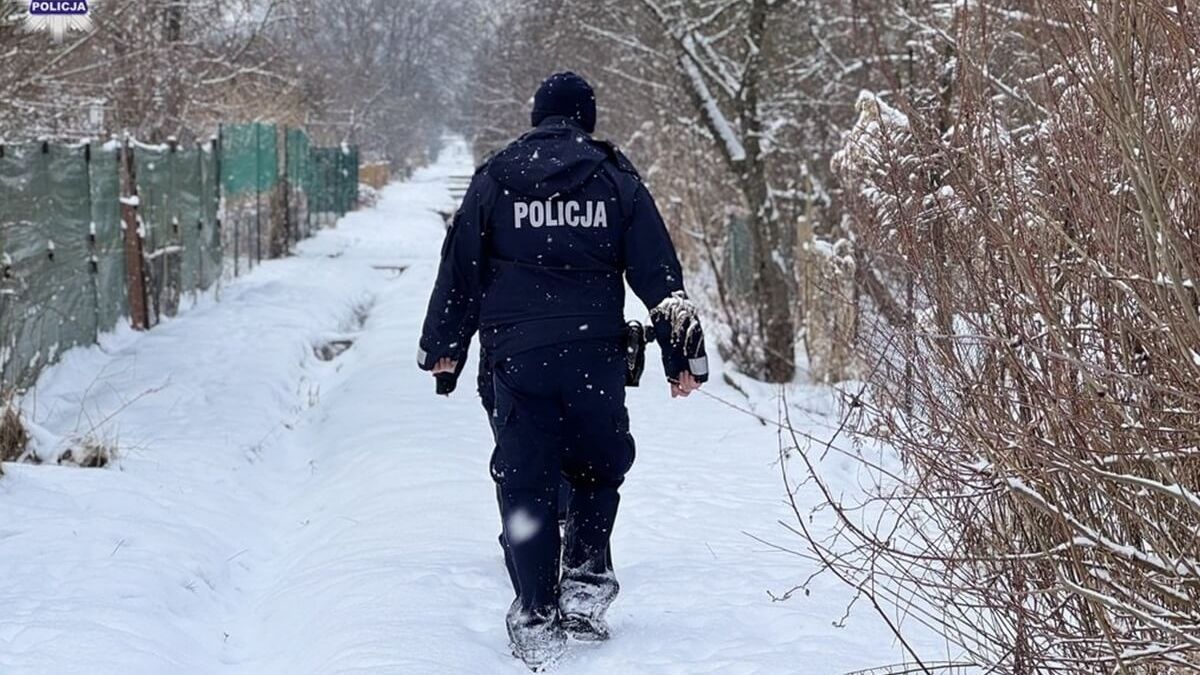 Policjant idący przez zaśnieżoną drogę