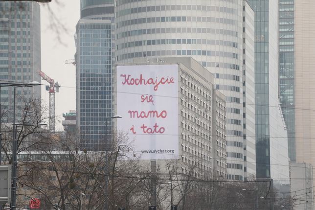 Warszawa. Aleja Jana Pawla II. Plakat z napisem ''Kochajcie się mamo i tato" Wspólnoty Trudnych Małżeństw Sychar