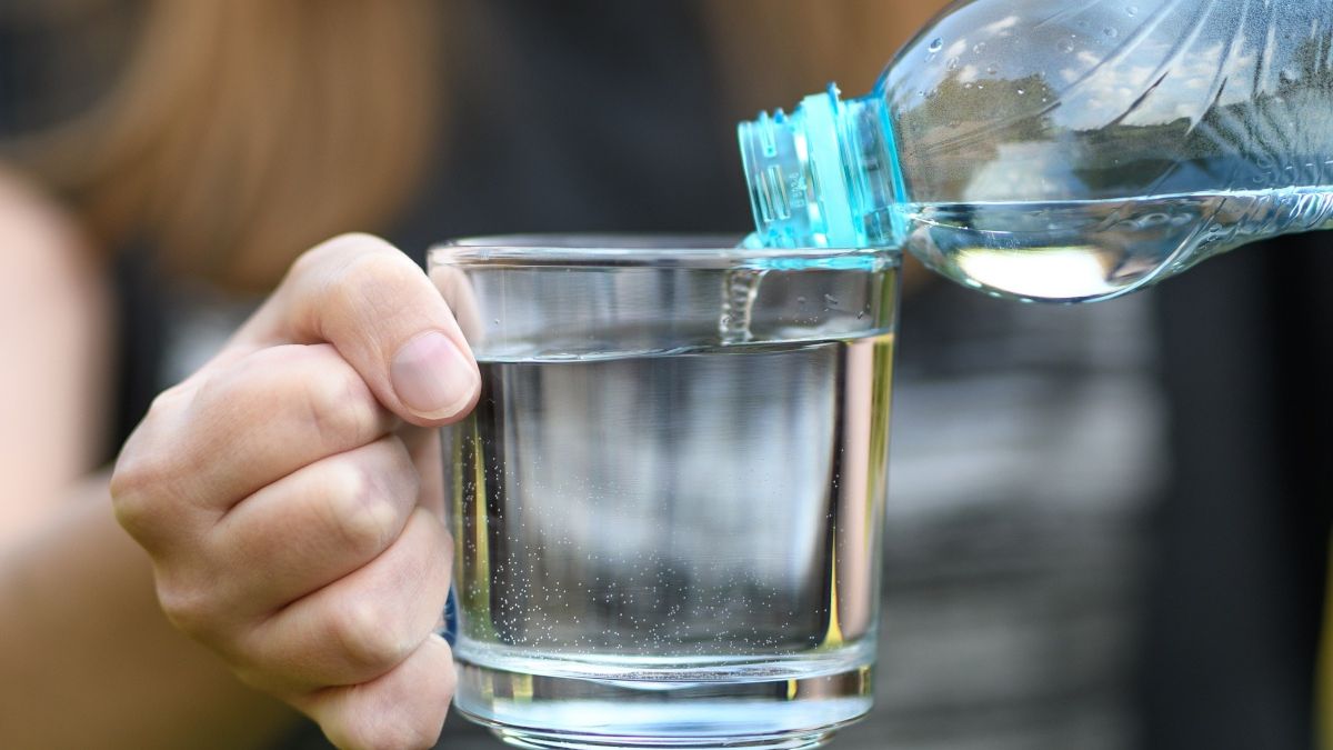 Kobieta lejąca wodę z butelki do szklanki