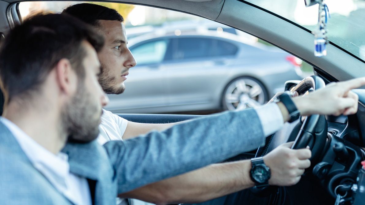 Driver's License Test.Driving school or test. Young man learning how to drive car together with her instructor.RealPeopleGroup
