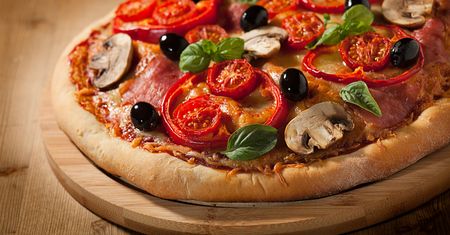 Upieczona mrożona pizza z mięsem i warzywami na tradycyjnym cieście