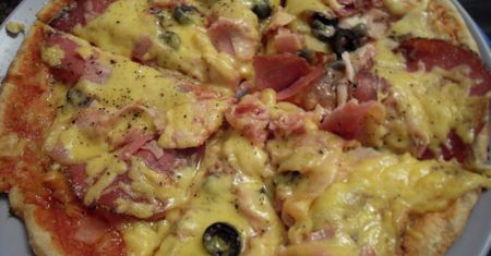 Upieczona mrożona pizza z mięsem i warzywami na grubym cieście