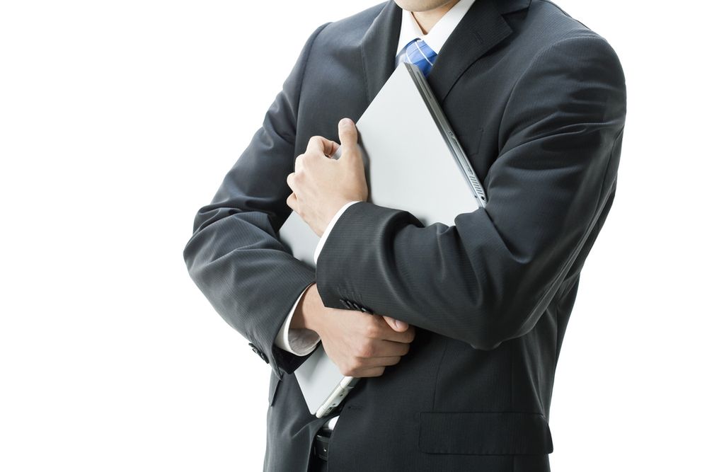 Zdjęcie Businessman holding laptop pochodzi z serwisu Shutterstock