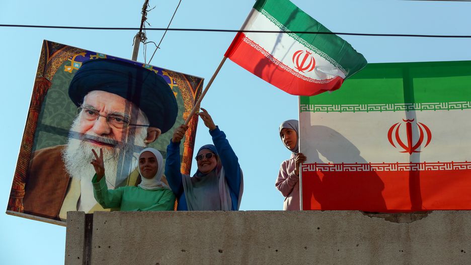 People stand between a picture of Iran's Supreme Leader, Ayatollah Ali Khamenei (L) and Iranian flags (R) during a celebration organized by Hezbollah in front of the Iranian Embassy in Beirut, Lebanon, 25 June 2025. Supporters of Hezbollah gathered in solidarity with the Iranian people, their political and military leadership, and Iran's Supreme Leader, Ayatollah Ali Khamenei, as they celebrated what they considered the victory of Iran against Israel and the US after US President Donald Trump announced a ceasefire between Israel and Iran. EPA/WAEL HAMZEH Dostawca: PAP/EPA.