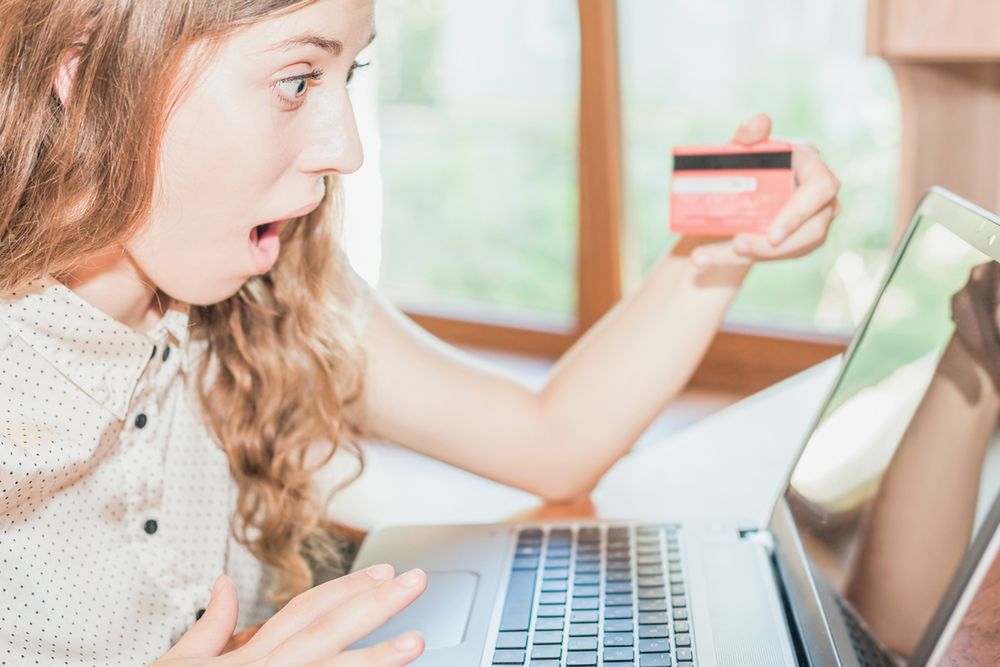 Zdjęcie Beautiful woman surprised holding credit card pochodzi z serwisu Shutterstock