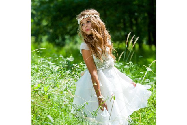 Dziewczynki przystępujące do Pierwszej Komunii najlepiej prezentują się w naturalnych i dziewczęcych fryzurach. Lekko podkręć włosy albo zrób warkocza i koniecznie dodaj wianek z żywych kwiatów