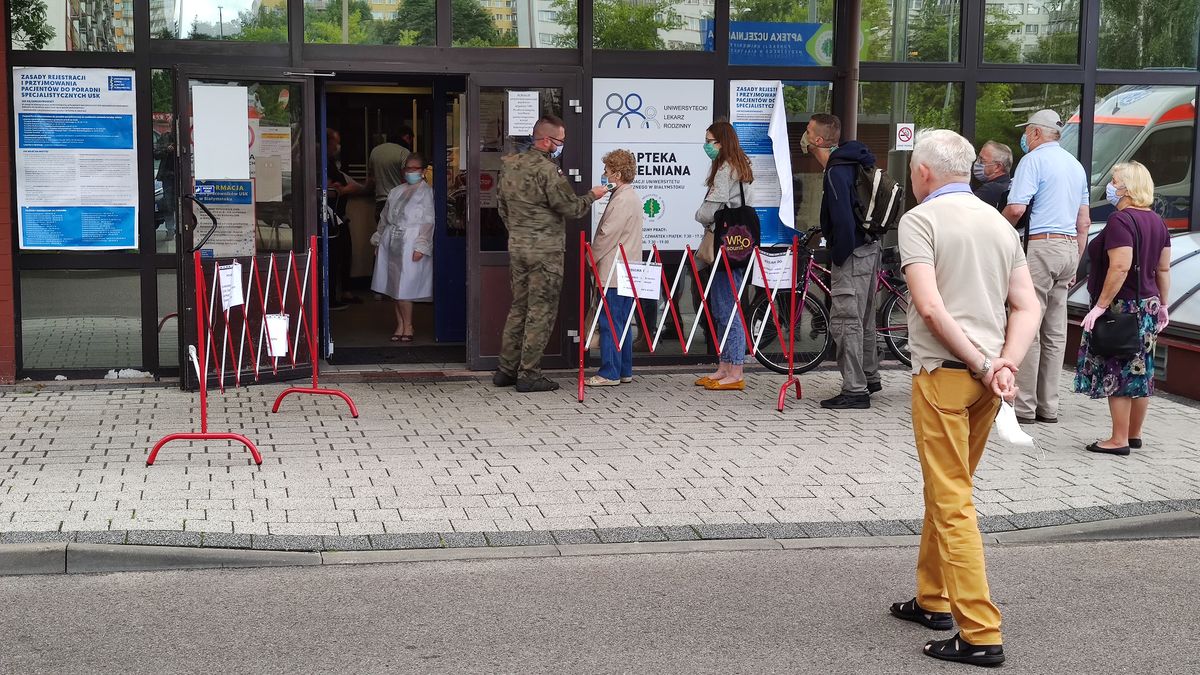 Bialystok, 13.07.2020.  Uniwersytecki Szpital Kliniczny w Bialymstoku USK przyjmuje pacjentow do przychodni przyszpitanych po wstepnej kwalifikacji, wypelnieniu oswiadczenia i zmierzeniu temperatury. N/z kolejka przed wejsciem i mierzenie temperatury przez zolnierza