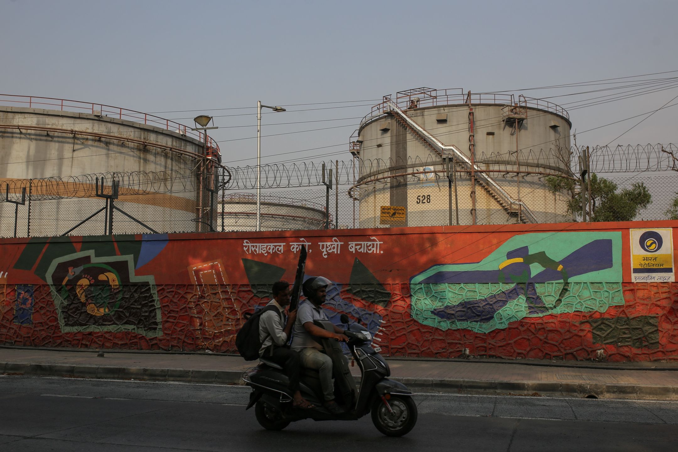 A motorist rides past an oil refinery operated by Bharat Petroleum Corp. Ltd., in Mumbai, India,  on Friday, April 4, 2025. Indian refiners have rushed back to the market to seek crude supply after President Donald Trump's threat of more penalties against Russia raised concerns over potential disruptions to oil flows. Photographer: Dhiraj Singh/Bloomberg via Getty Images
