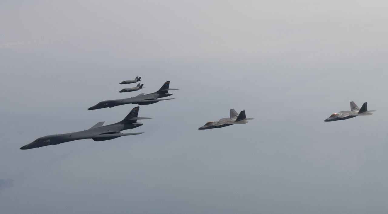 UNDISCLOSED LOCATION, SOUTH KOREA - FEBRUARY 01: In this handout image released by the South Korean Defense Ministry, U.S. Air Force B-1B bombers (L), F-22 fighter jets and South Korean Air Force F-35 fighter jets (top) fly over South Korea Peninsula during a joint air drill on February 01