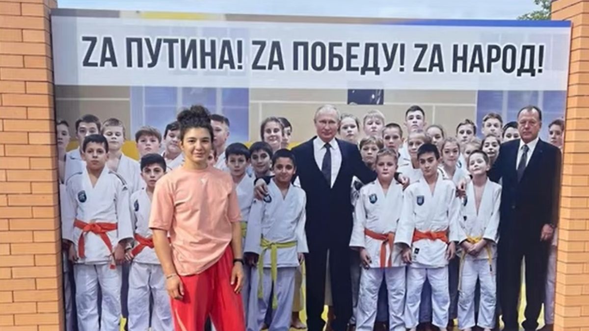 Madina Tajmazowa pozująca na tle plakatu z Putinem