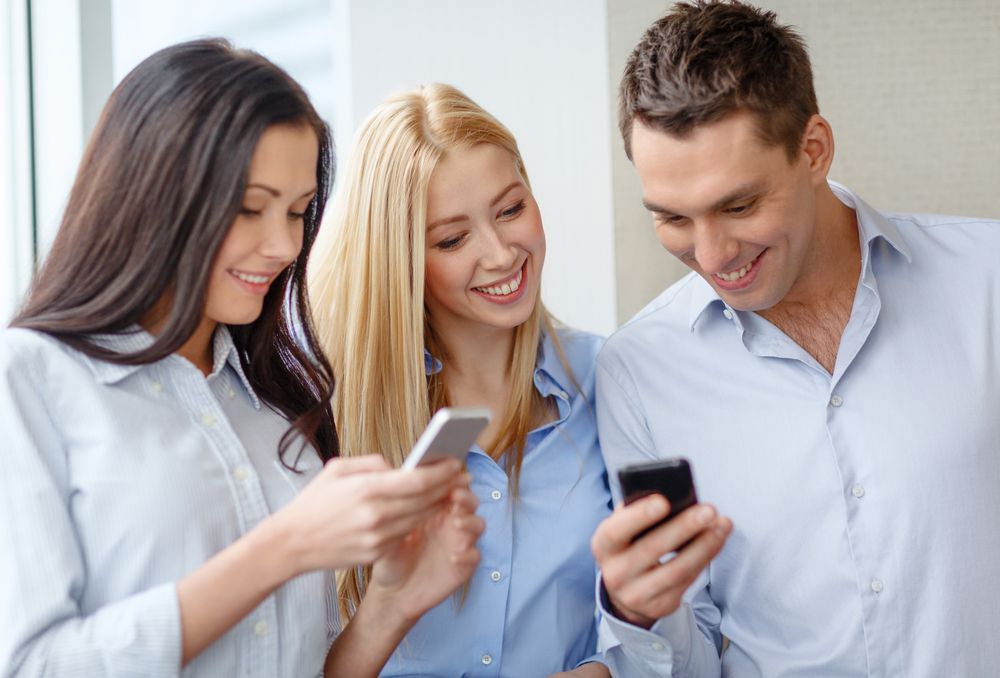 Smiling business team with smartphones