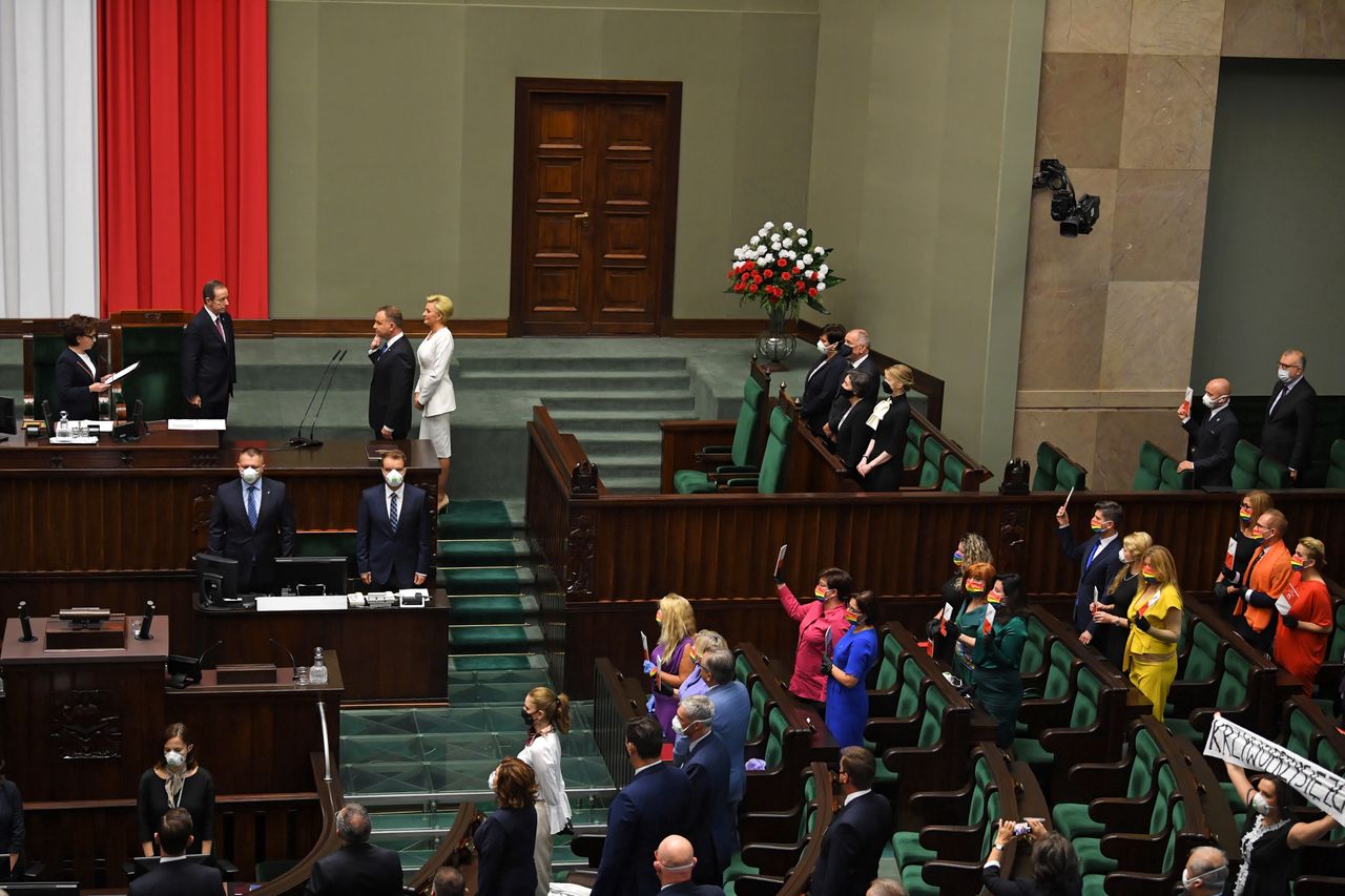 Zaprzysiężenie Andrzeja Dudy. Posłowie Lewicy z egzemplarzami konstytucji, Klaudia Jachira z transparentem "Krzywoprzysięzca"