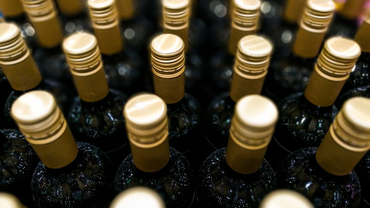 Close up overhead view of large collection of glass wine bottles with gold screw capsClose up color image depicting an overhead view of a large collection of dark colored glass wine bottles with gold-colored screw caps. Selective focus is on the row of bottles in the middle, while the other bottles are nicely thrown out of focus. Room for copy space.coldsnowstorm