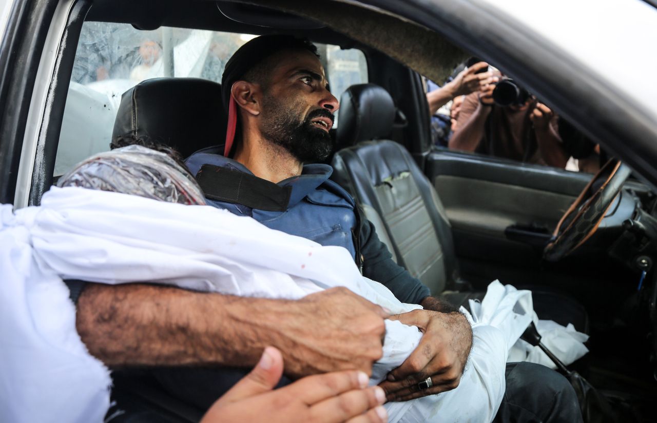 Mohammed Alaloul is holding the corpse of one of the children.