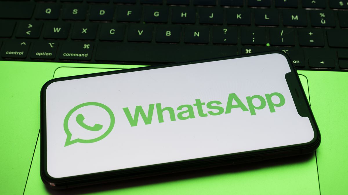 In Créteil, France, on September 29, 2025, the WhatsApp logo appears on a smartphone placed on a laptop keyboard, which reflects a green light. Meta, the parent company of WhatsApp and Meta AI, makes the Artificial Intelligence assistant mandatory in its instant messaging app. (Photo Illustration by Samuel Boivin/NurPhoto via Getty Images)