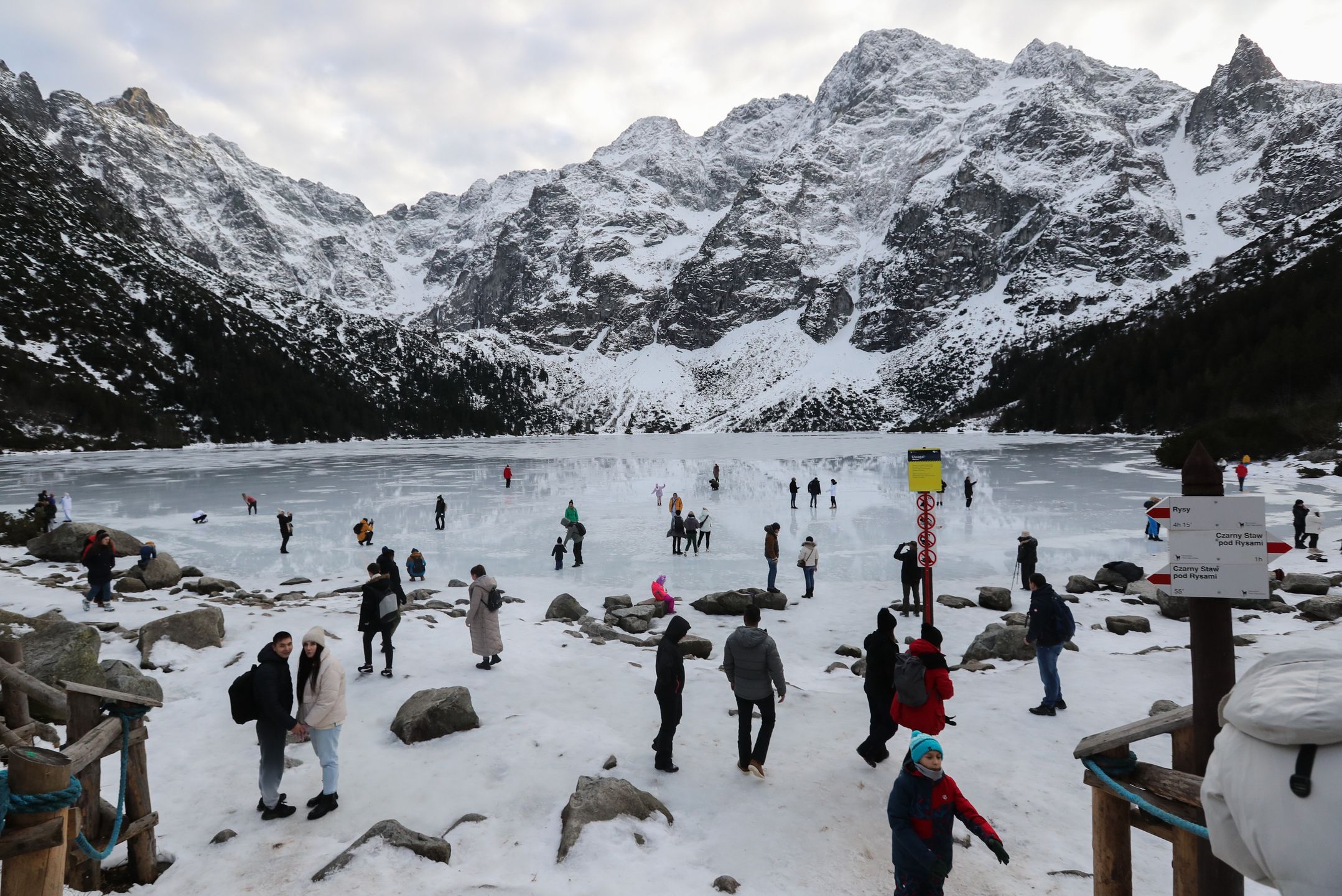Tatry, Morskie Oko, 26.12.2022. Turyści na tafli lodu na jeziorze Morskie Oko w Tatrach, 26 bm. Tatrzański Park Narodowy ostrzega przed wchodzeniem na zamarznięte górskie jeziora � z powodu panujących w ciągu dnia dodatnich temperatur lód jest bardzo cienki i grozi załamaniem. (jm) PAP/Grzegorz Momot