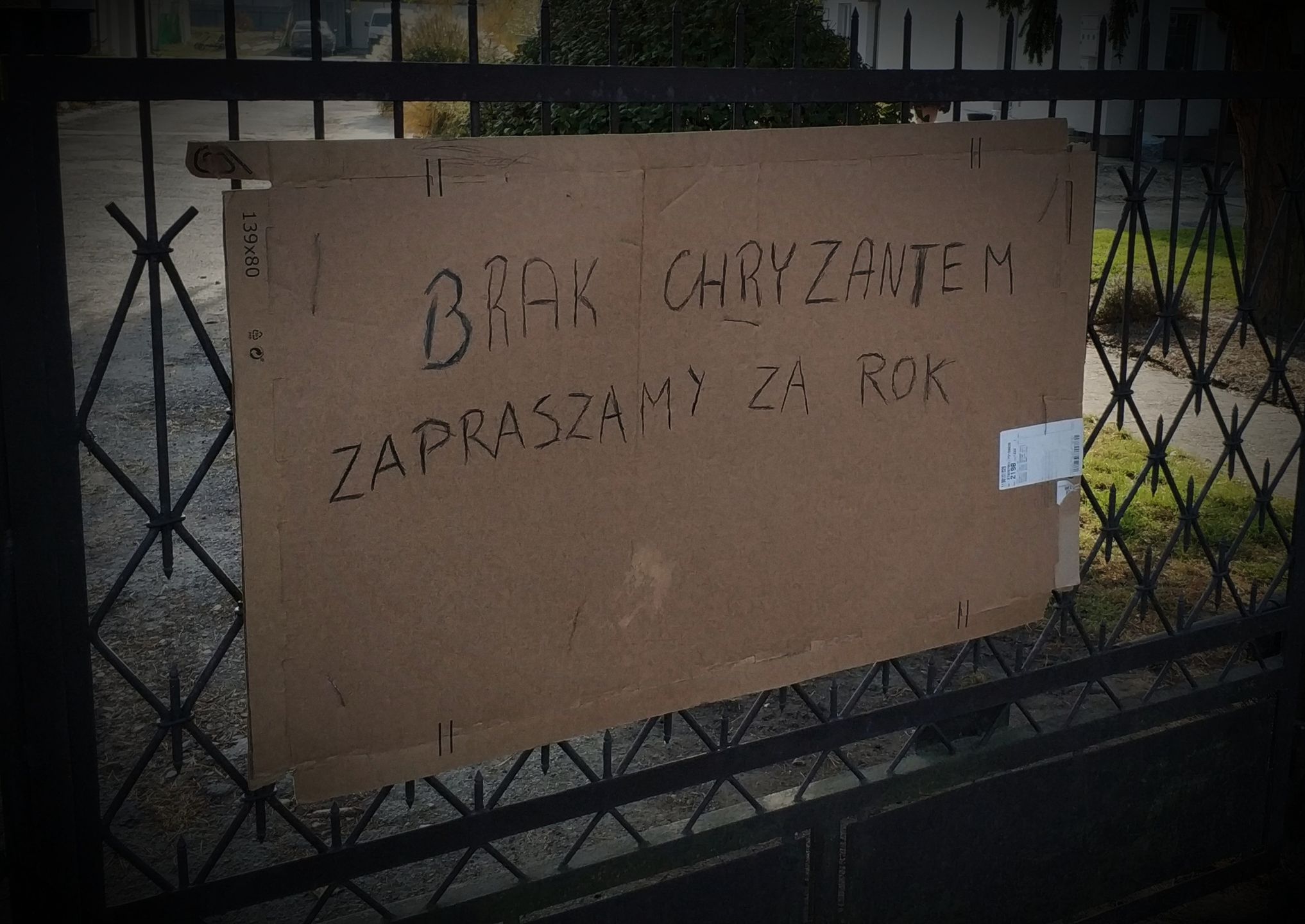 Zdjęcie przedstawia bramę z wywieszoną na niej informacją o braku chryzantem