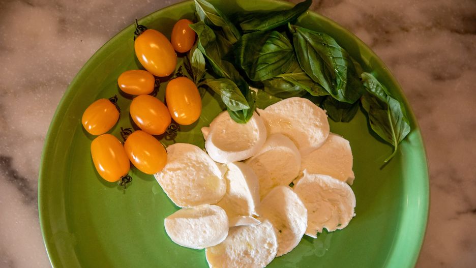 A plate containing slices of mozzarella, fresh basil and yellow cherry tomatoes for pizza toppings at a pizzeria in Naples, Italy on Thursday, Feb. 2, 2023. Enjoying one of Italys classic dishes has just become noticeably more expensive, with the average cost of cooking a Pizza Margherita up almost 30% in December from year ago. Photographer: Alessio Paduano/Bloomberg via Getty Images