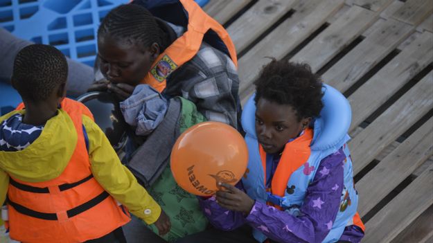 Mali imigranci bawią się balonami po tym, jak zostali uratowani podczas akcji ratunkowej na libijskim wybrzeżu