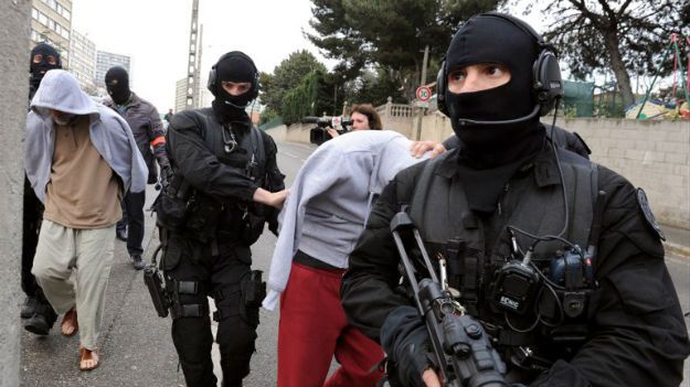 Francuscy policjanci prowadzą zatrzymanych podejrzanych o przynależność grupy islamistycznej