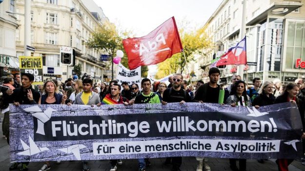 Manifestujący trzymają baner z napisem "Witamy uchodźców".