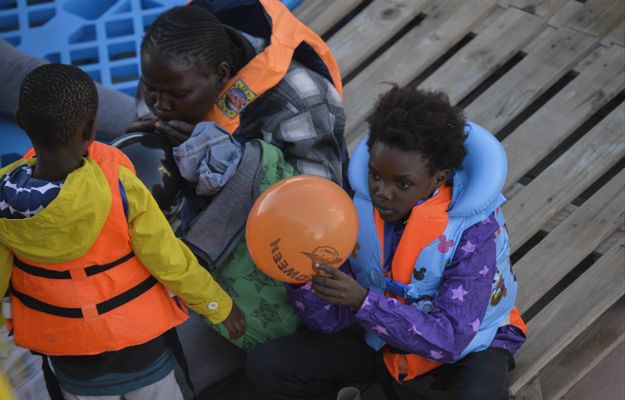 Mali imigranci bawią się balonami po tym, jak zostali uratowani podczas akcji ratunkowej na libijskim wybrzeżu