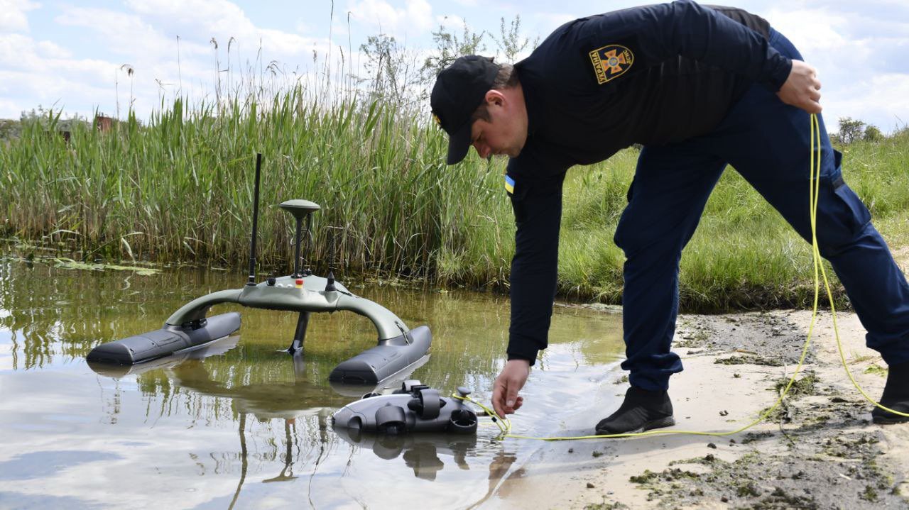 Ukraiński saper wykorzystujący dona "Sonobot 5 do wyszukiwania min w zbiorniku wodnym.