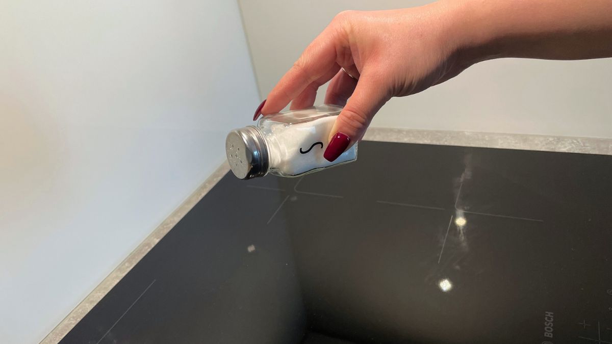Ręka sypie sól na płytę indukcyjną